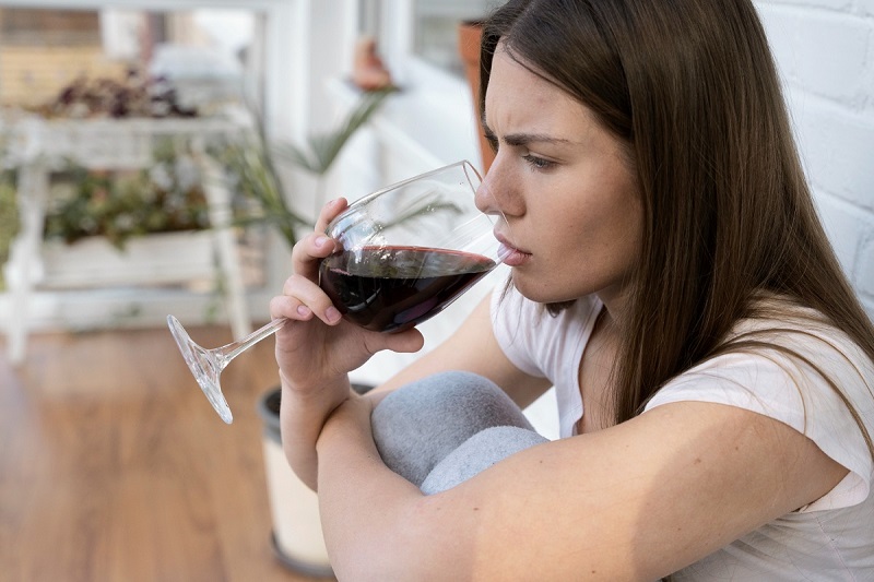Una mujer consumiendo alcohol sentada en el suelo
