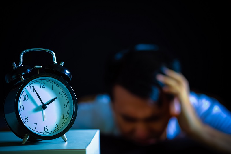 un hombre pensando en el tiempo de elminación de la coca frente a un reloj